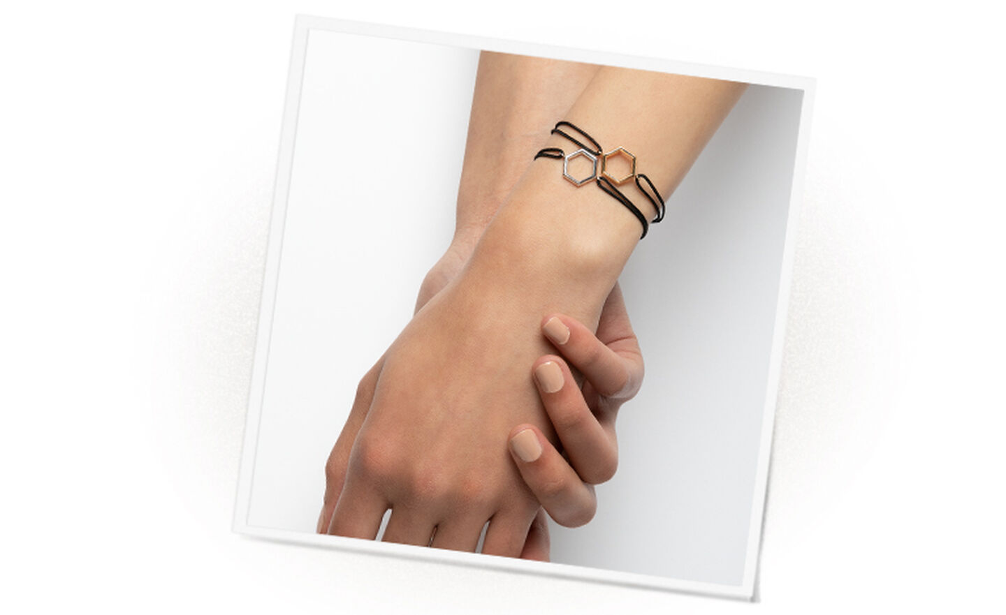 Holding hands wearing two silver and gold hexagonal pendant bracelets
