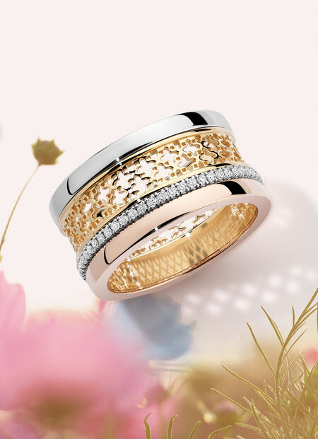 Birks Dare to Dream tri-gold ring on a floral background.