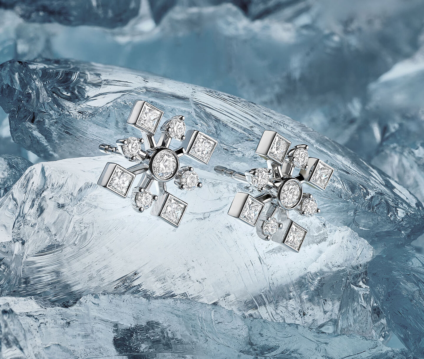 Birks Snowflake diamond earrings on a snowy background,