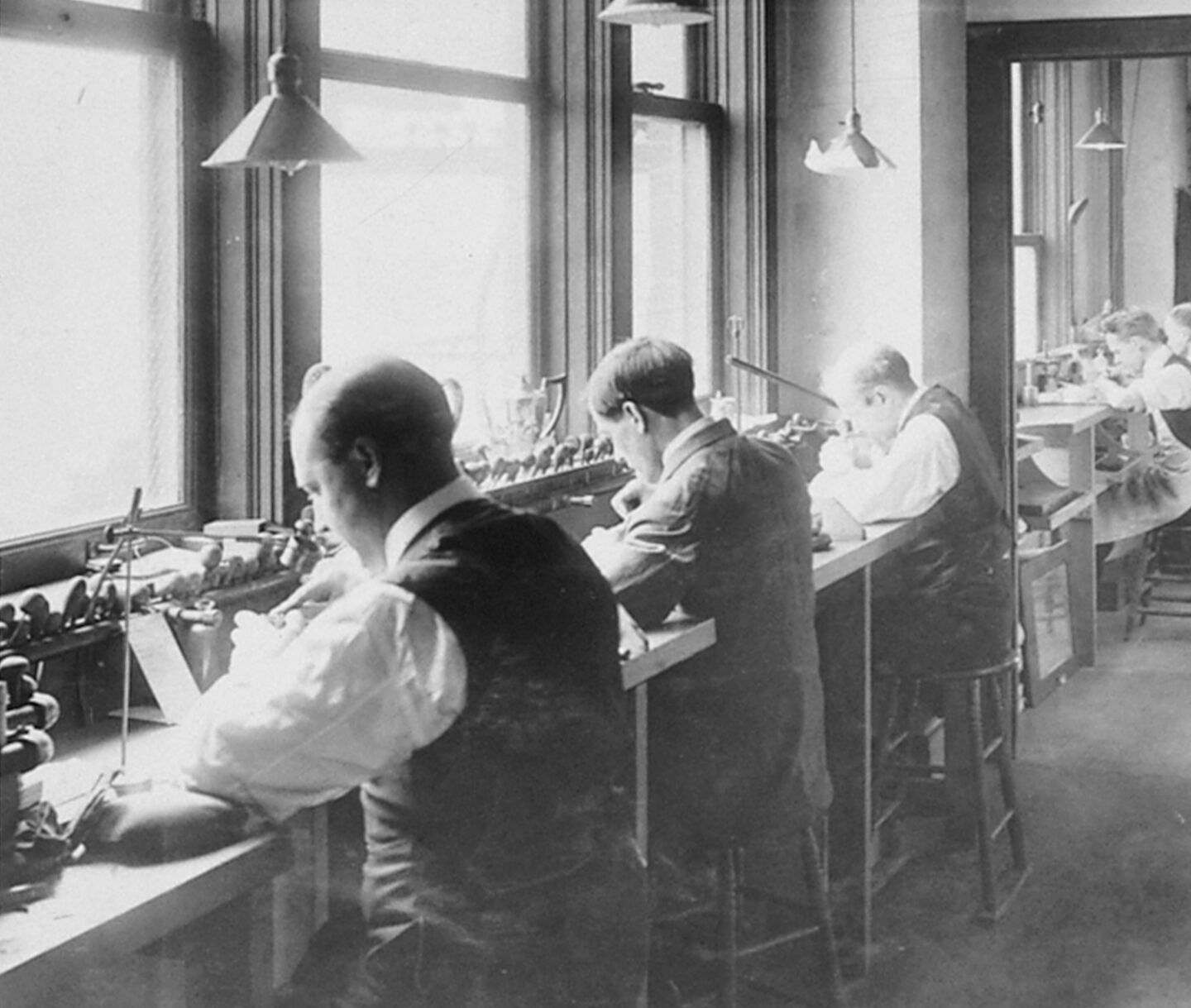 Black and white photo of craftsmen working at a table.