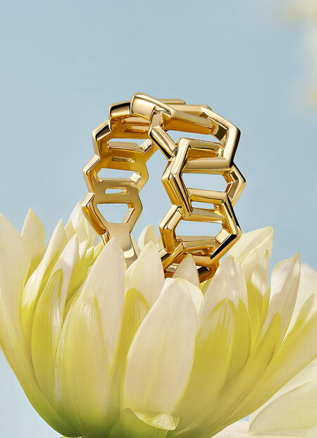 A Birks Bee Chic gold ring resting on a flower.