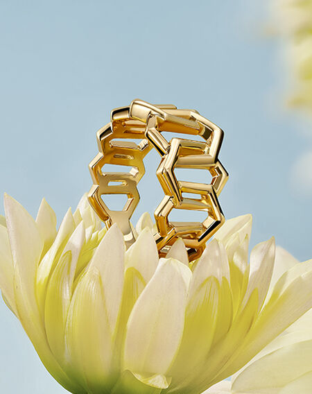 Birks Bee Chic yellow diamond ring place on top of a white-yellow flower on a light blue background
