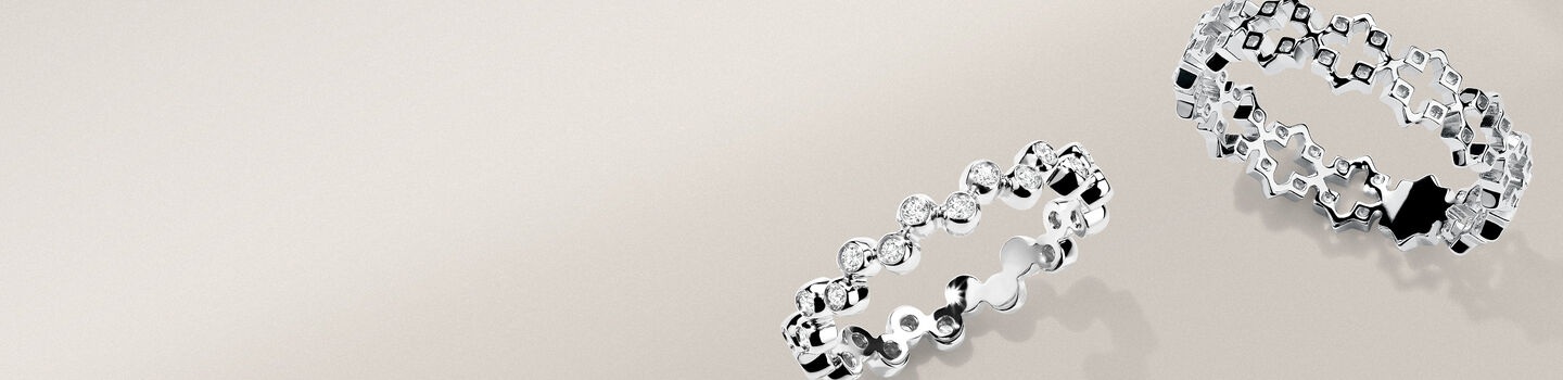 The Birks Iconic white gold diamond Splash ring and silver Muse ring on a greyish-beige background