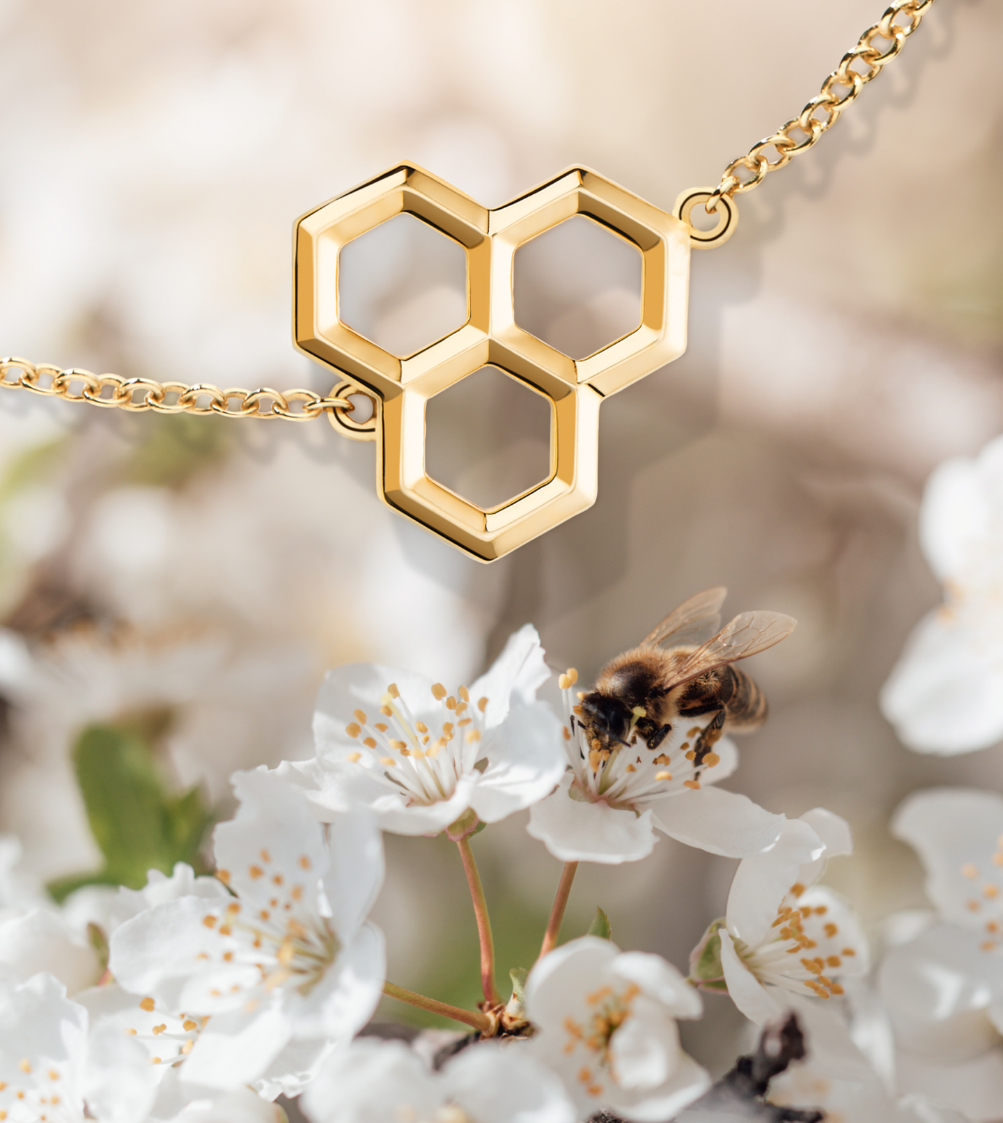 Gold jewelry in front of a bee gathering pollen from a white flower.
