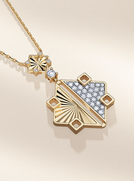Birks Muse Gold and Diamond Drop Necklace on a beige background.